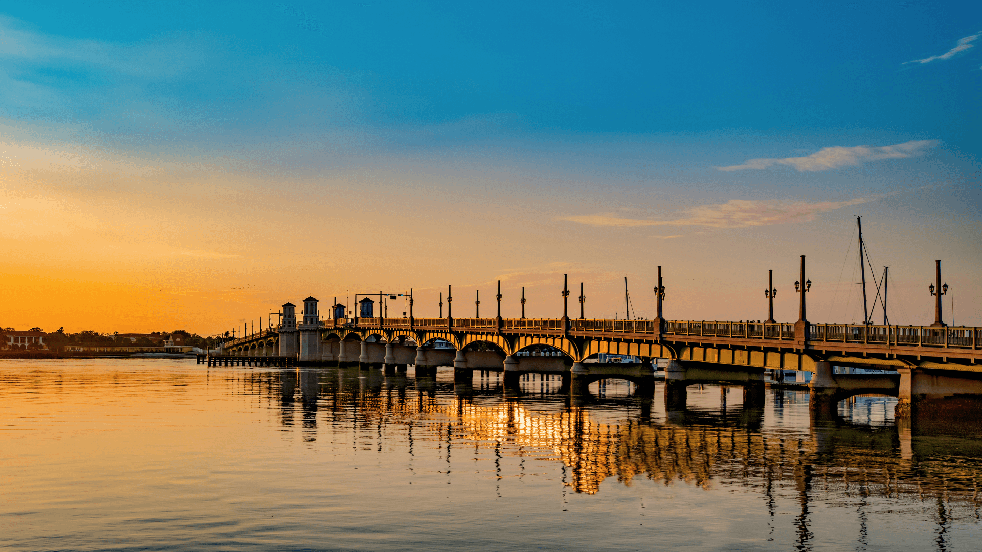 A sunset view of a bridge reflecting in calm waters.