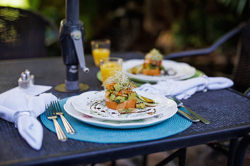 A beautifully arranged plate of food sits on a table with utensils, napkins, and a glass of orange juice.