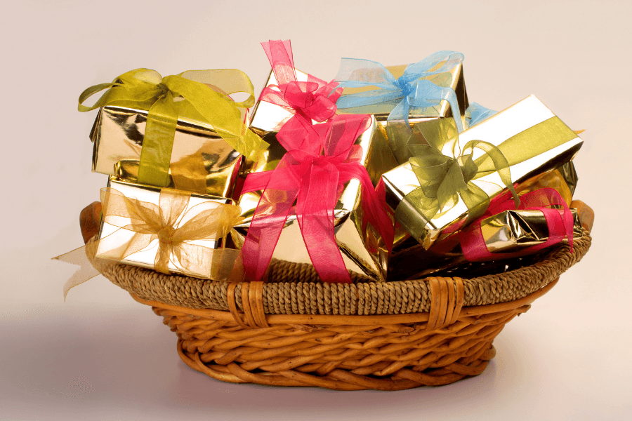 A wicker basket filled with gold-wrapped gifts tied with colorful ribbons.