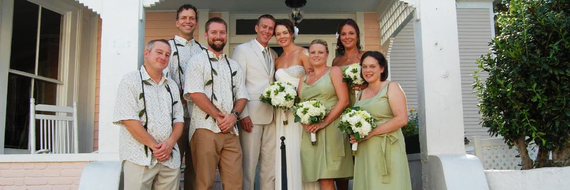 A wedding party posing outside a house.