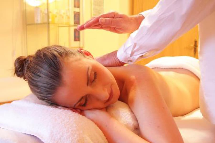 A woman receiving a massage, lying face down on a table with her eyes closed.